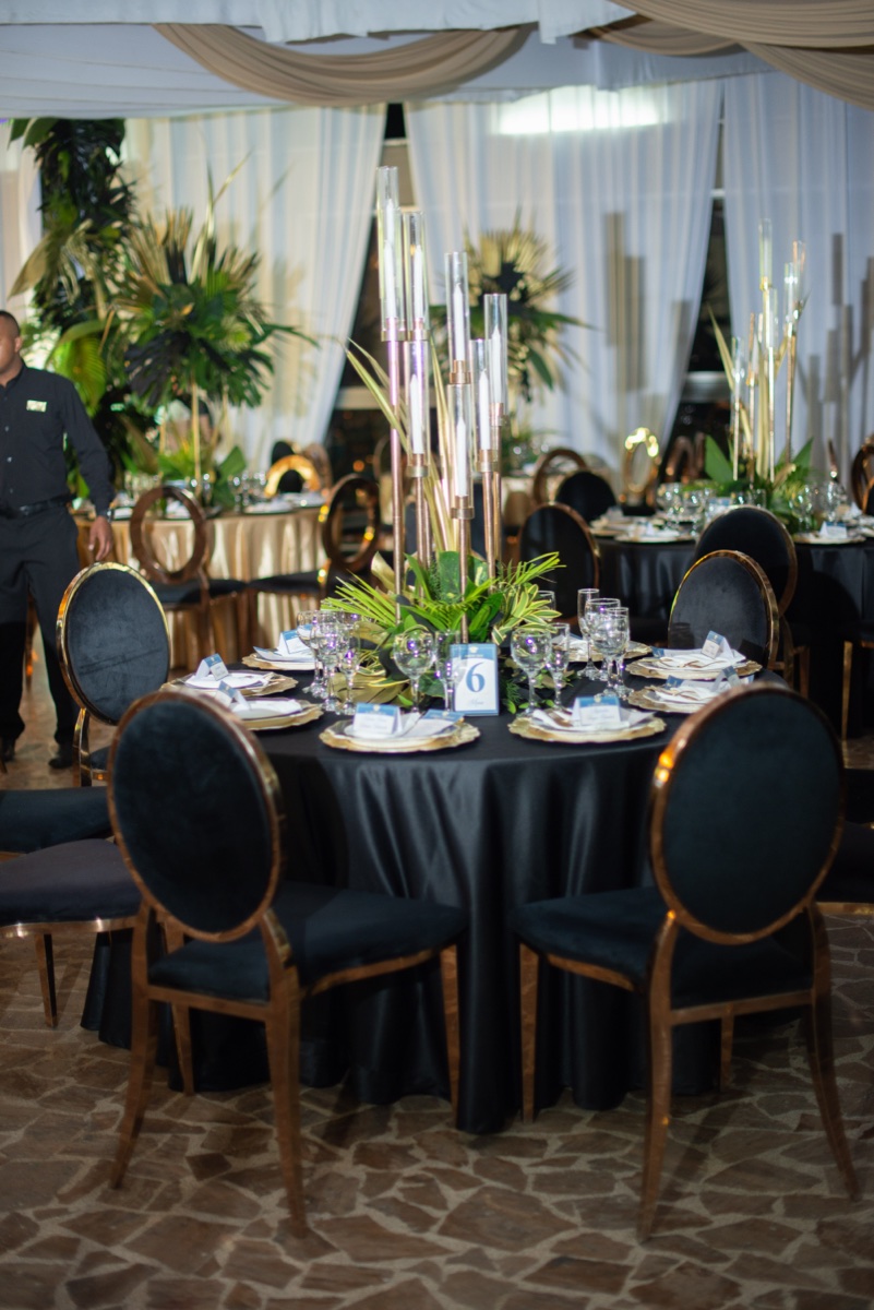 Montaje de mesa imperial con mantel negro y sillas doradas